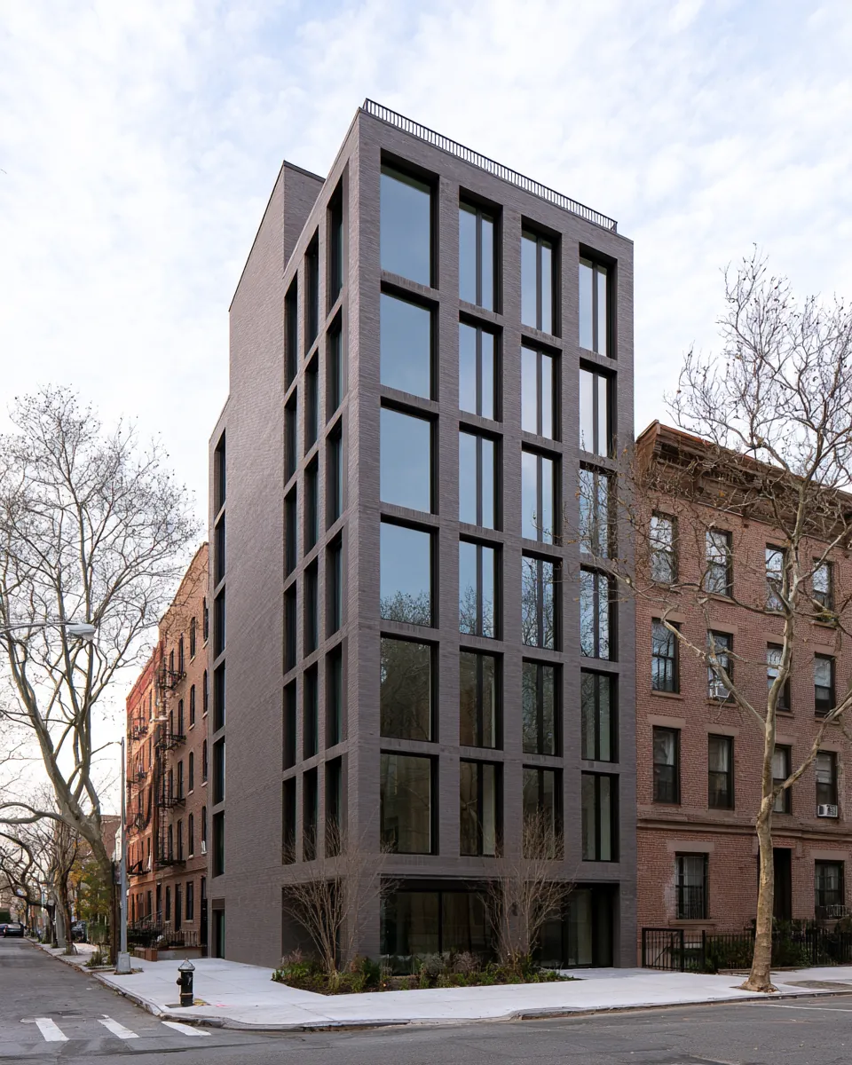 Typology study: eight-story apartment building on a corner beside older brick neighbors.